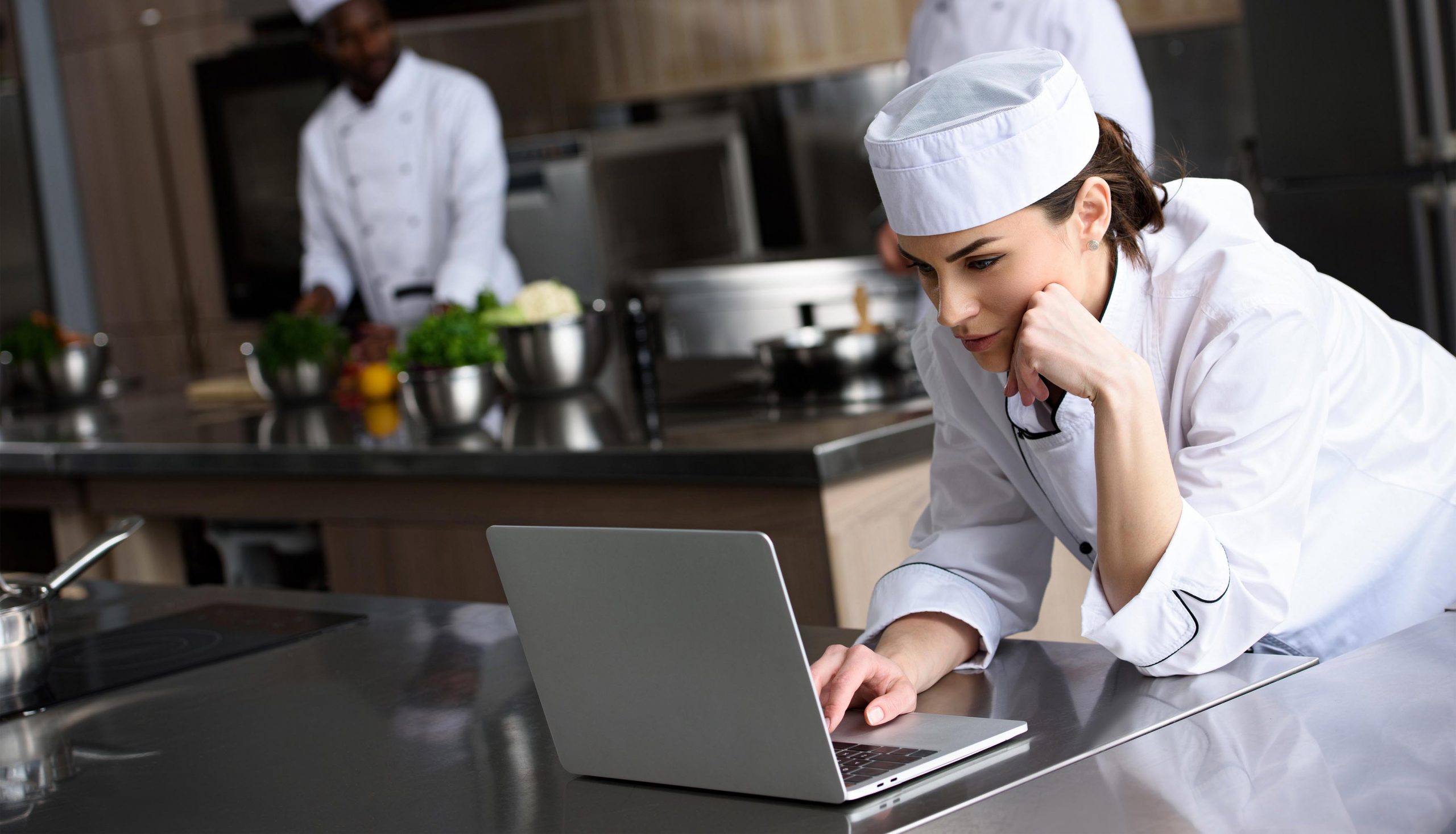 attractive chef using laptop at restaurant kitchen
